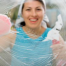 Woman cleaning window with a smiling face
