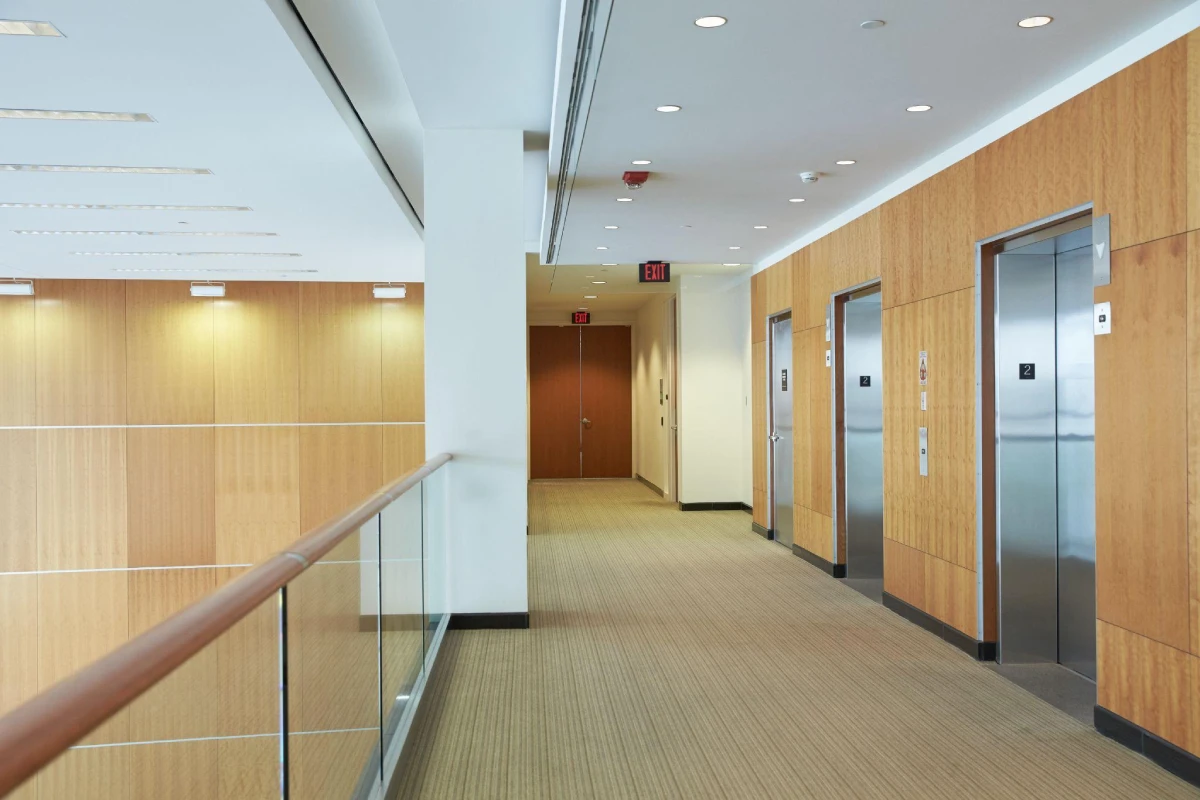 An image of a commercial building's corridor, with several lifts parked aside. The corridor has carpet flooring
